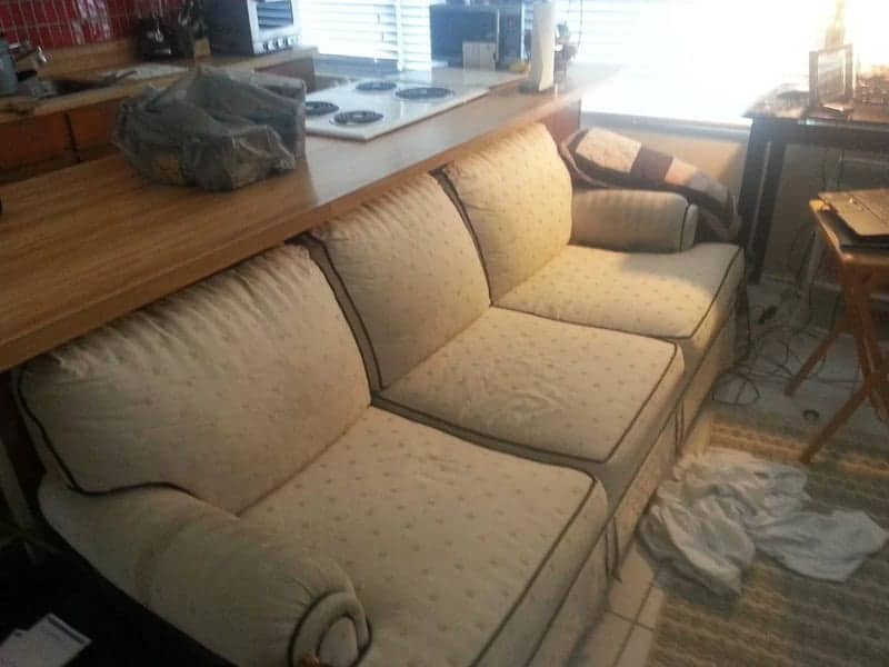 Cream patterned floral sofa tucked partially under a low kitchen breakfast bar counter.