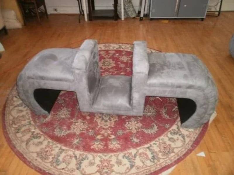 Symmetrical gray sofa with two high backrests in the center facing outward.