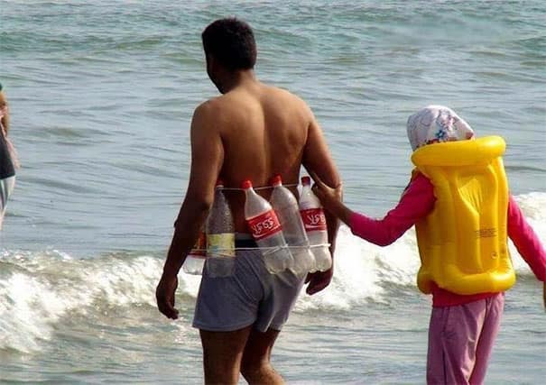 A DIY-inspired vacation meme shows a man entering the ocean waves wearing a makeshift flotation belt constructed out of empty plastic two-liter Coca-Cola bottles tied around his torso.