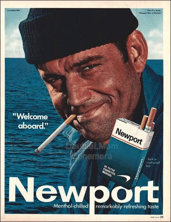 A rugged vintage cigarette ad for Newport menthol cigarettes featuring a close-up of a weather-beaten sailor in a beanie, smiling with a cigarette in his mouth against a blue ocean background.