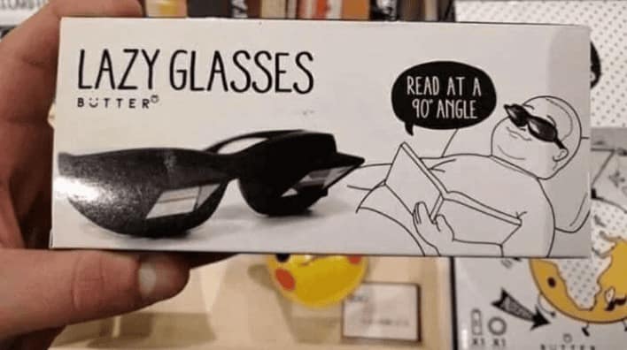 A product box for "Lazy Glasses," featuring prismatic lenses that allow the wearer to lie completely flat on their back while reading a book held at a 90-degree angle.
