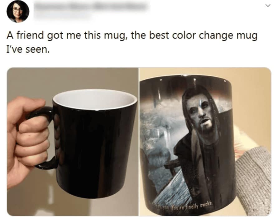 A two-panel image of a weird product color-change mug; when cold, it is solid black, but when hot liquid is added, it reveals the iconic Skyrim opening scene with the text "Hey you, You’re finally awake."