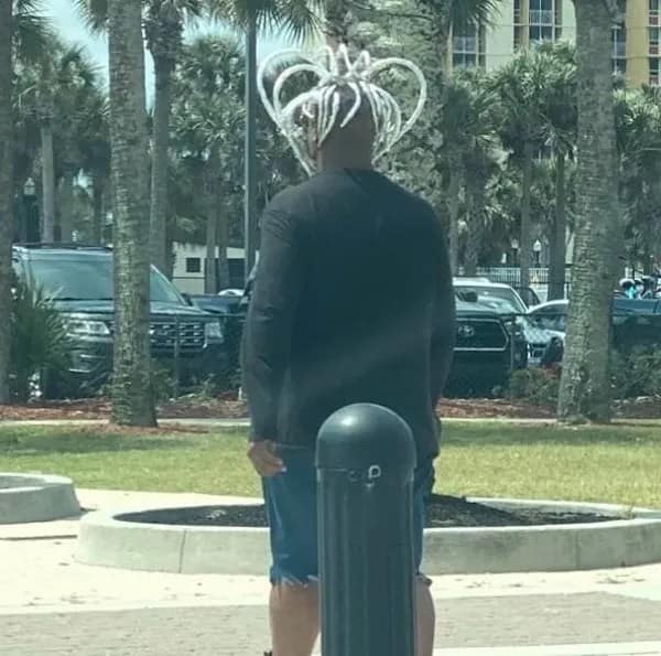 Man seen from behind with white dreadlocks styled into large curved loops forming a crown shape, an elaborate haircut fail.