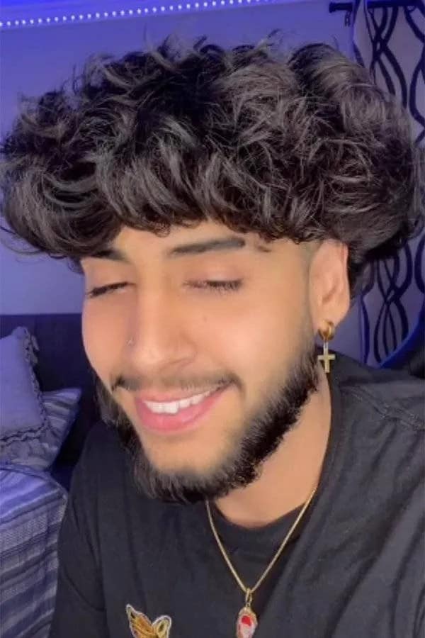 Young man smiling with an oversized, fluffy curly bowl cut and closely shaved sides under a haircut fail category.