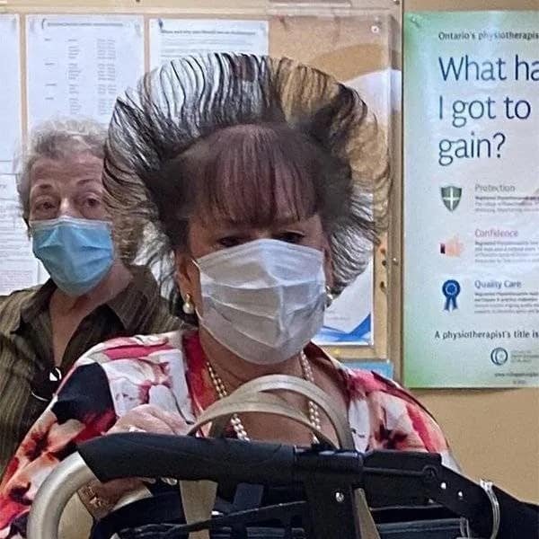 Woman wearing a face mask with an enormous, circular see-through beehive blowout hairstyle, demonstrating extreme bad haircuts.