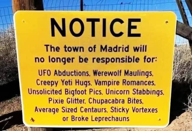 Hilarious yellow notice sign listing absurd mythical liabilities for the town of Madrid.
