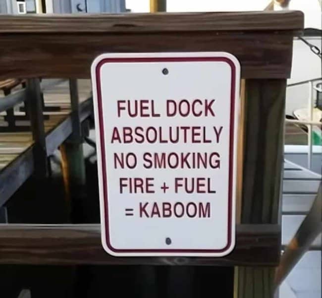 Humorous fuel dock safety sign explaining that fire and fuel equals kaboom.