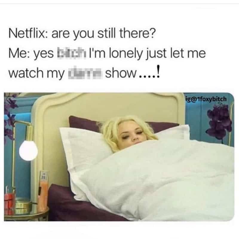 Television screenshot of a woman in bed looking annoyed under a white duvet blanket.