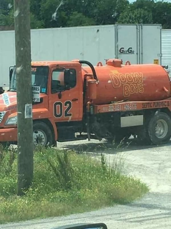 Large orange septic pumping truck creatively painted to parody the General Lee as The Dooky Boys.