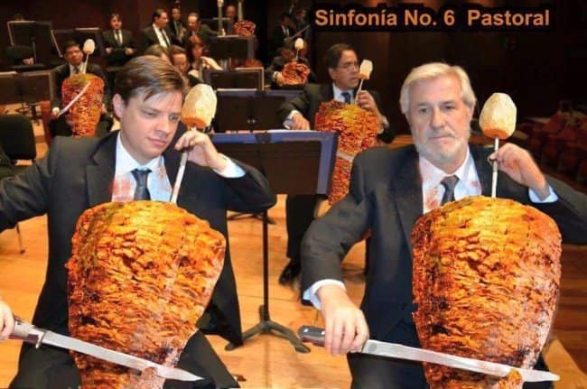 surreal british meme depicts a classical orchestra transformed into a late-night kebab shop fever dream. Musicians in formal tuxedos are photoshopped holding bows and playing massive, rotating vertical spits of seasoned Döner kebab meat as if they were cellos and violins, complete with carving knives. The top text dryly reads, "Sinfonía No. 6 Pastoral," celebrating the UK's ultimate post-pub comfort food.