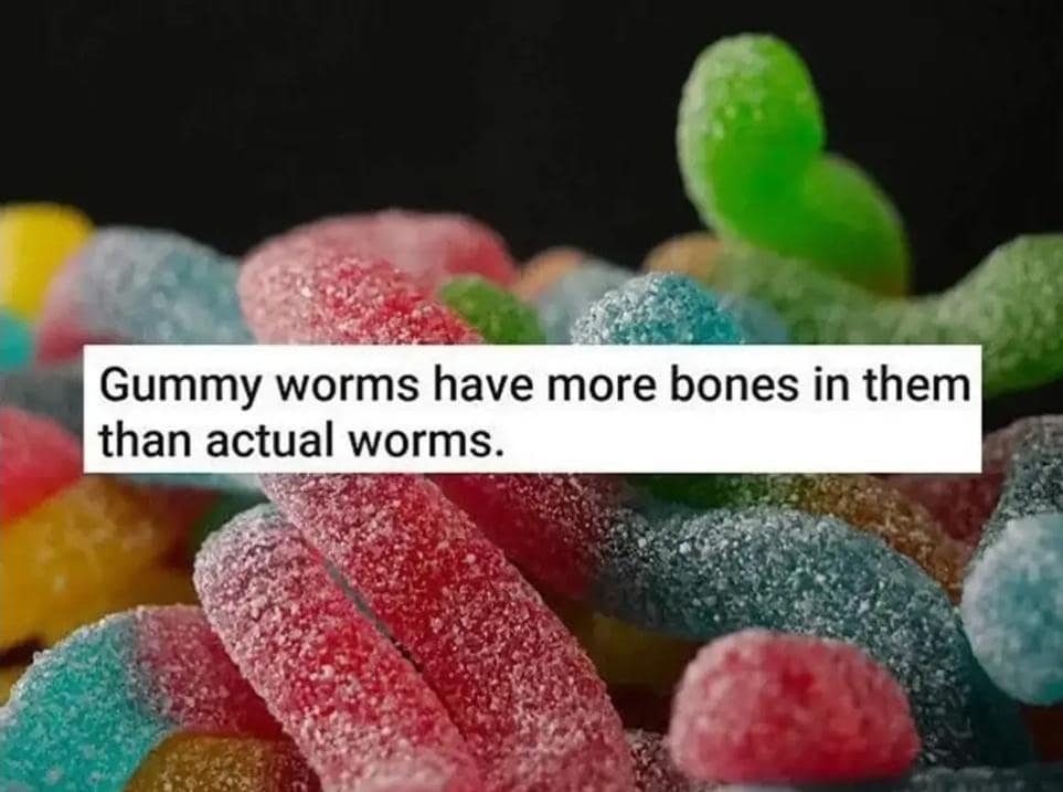 A dark-humor food-fact classic meme displaying a colorful pile of sugar-dusted sour gummy worms under a white text box that dryly reads, "Gummy worms have more bones in them than actual worms."