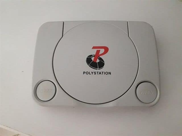 A close-up shot of a vintage gray hardware clone console from our archive of old memes reveals a cheap plastic casing branded as a "POLYSTATION," designed to explicitly mimic an original 1995 Sony PlayStation.