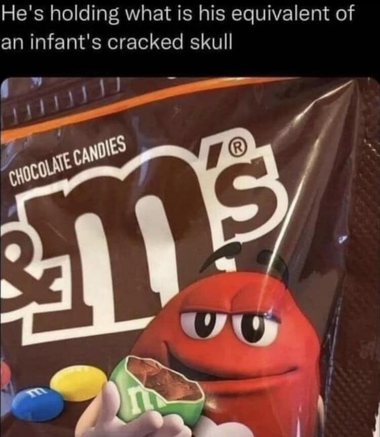 bizarre marketing perspective crop operating as a classic meme close-ups a bag of M&M's candies, tracking the red character smiling next to a cracked green M&M under a comment comparing the sight to holding a cracked infant skull.