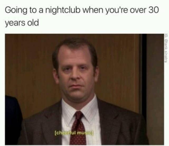 Toby Flenderson from The Office looking thoroughly drained, deadpan, and miserable under yellow closed captions reading "[cheerful music]" in a relatable aging classic meme titled, "Going to a nightclub when you're over 30 years old".