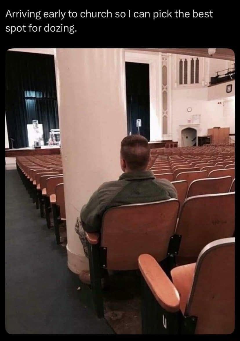 A man sitting in an empty auditorium or church pew strategically positioned directly behind a massive white concrete structural pillar to hide from the main stage in a classic meme.