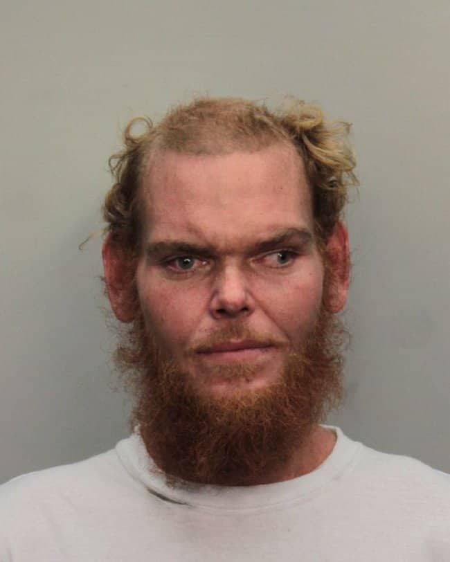 Close-up mugshot of a man with messy red hair and a scruffy red beard.