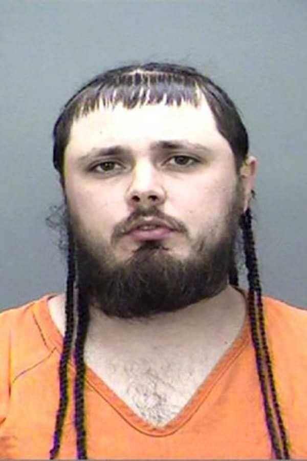 Mugshot of a man with short bangs on top and long thin braids hanging down.
