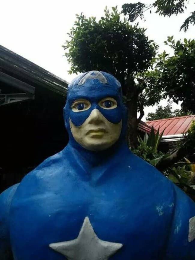 Close up of a poorly made blue superhero statue resembling an unsettled Captain America.