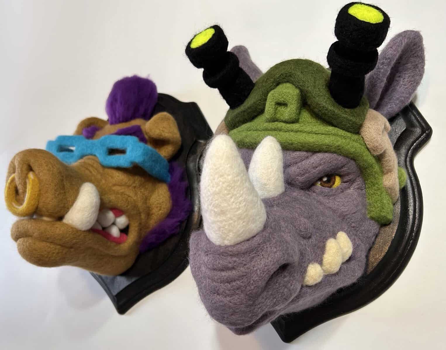 Highly detailed faux-taxidermy wall plaques showcasing the three-dimensional needle-felted heads of TMNT cartoon villains Bebop and Rocksteady, displaying an incredibly polished form of funny felt art.