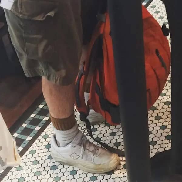Close-up of a dad wearing cargo shorts and double-layered white and brown crew socks with white New Balance sneakers.