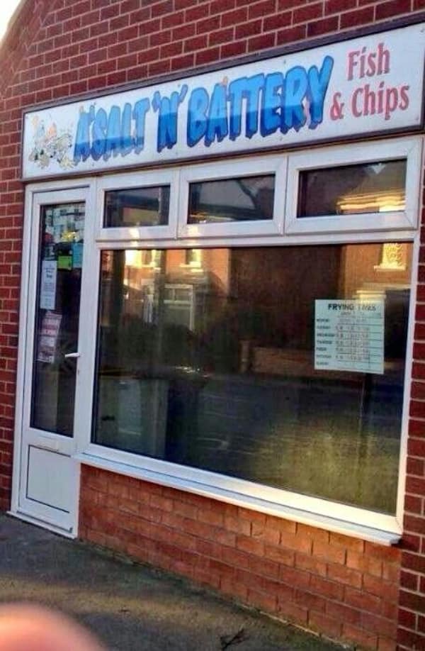 A real-world business sign captured as a dumb meme showcases a brick building storefront for a local fish and chips shop boldly named "A SALT 'N' BATTERY & Chips."