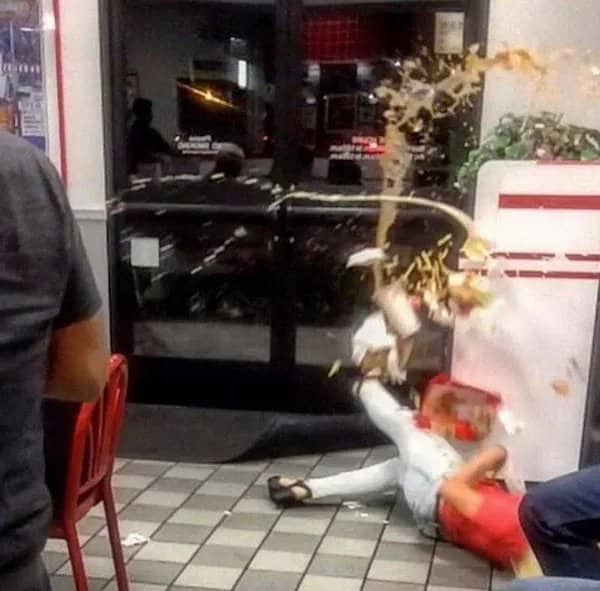 Mid-fall photograph of a person slipping in a restaurant while food and drinks splash everywhere.