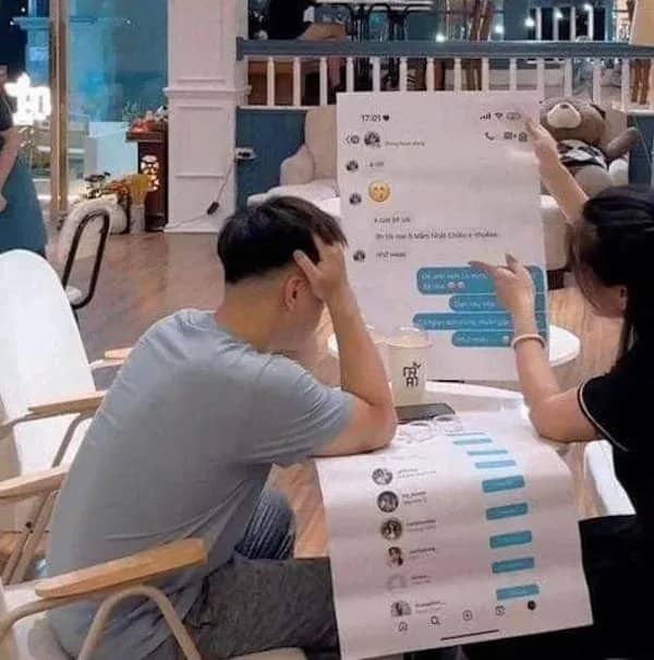 A man holding his head while a woman points at a massively enlarged printout of text messages.