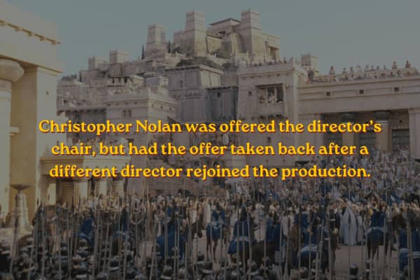 Massive ancient city walls of Troy teeming with soldiers, text notes director choices.