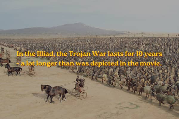 A massive army with chariots spread across a desert plain under a grey sky.