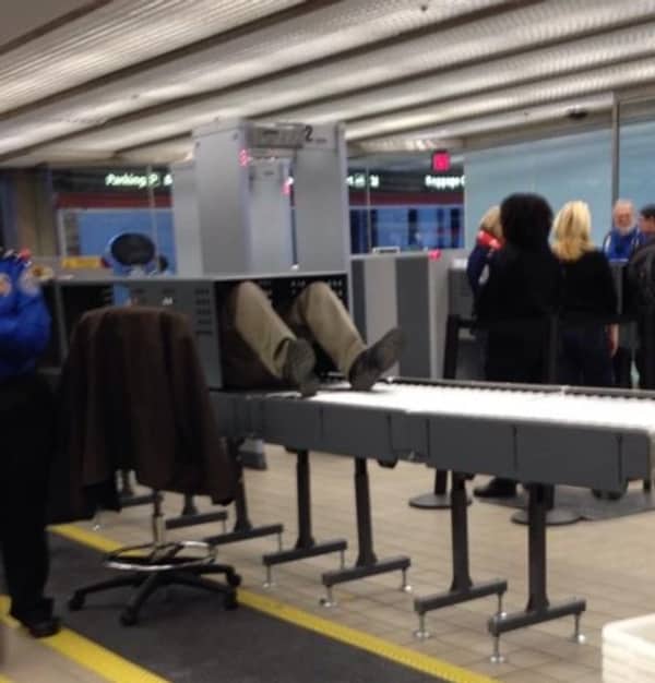 A passenger accidentally rides face down on the baggage carousel conveyor belt at airport security.