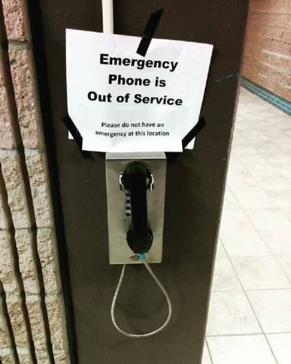 An out of service airport emergency phone with a sign telling passengers not to have emergencies.
