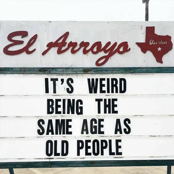 A roadside restaurant marquee sign stating it is weird being the same age as old people.