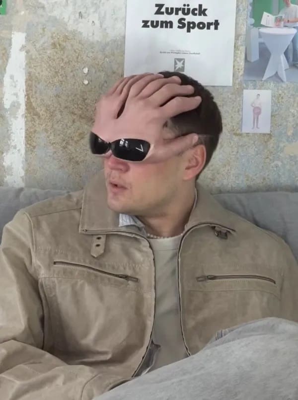 Bizarre optical illusion image featuring a realistic hand shaped mask with sunglasses on a man.