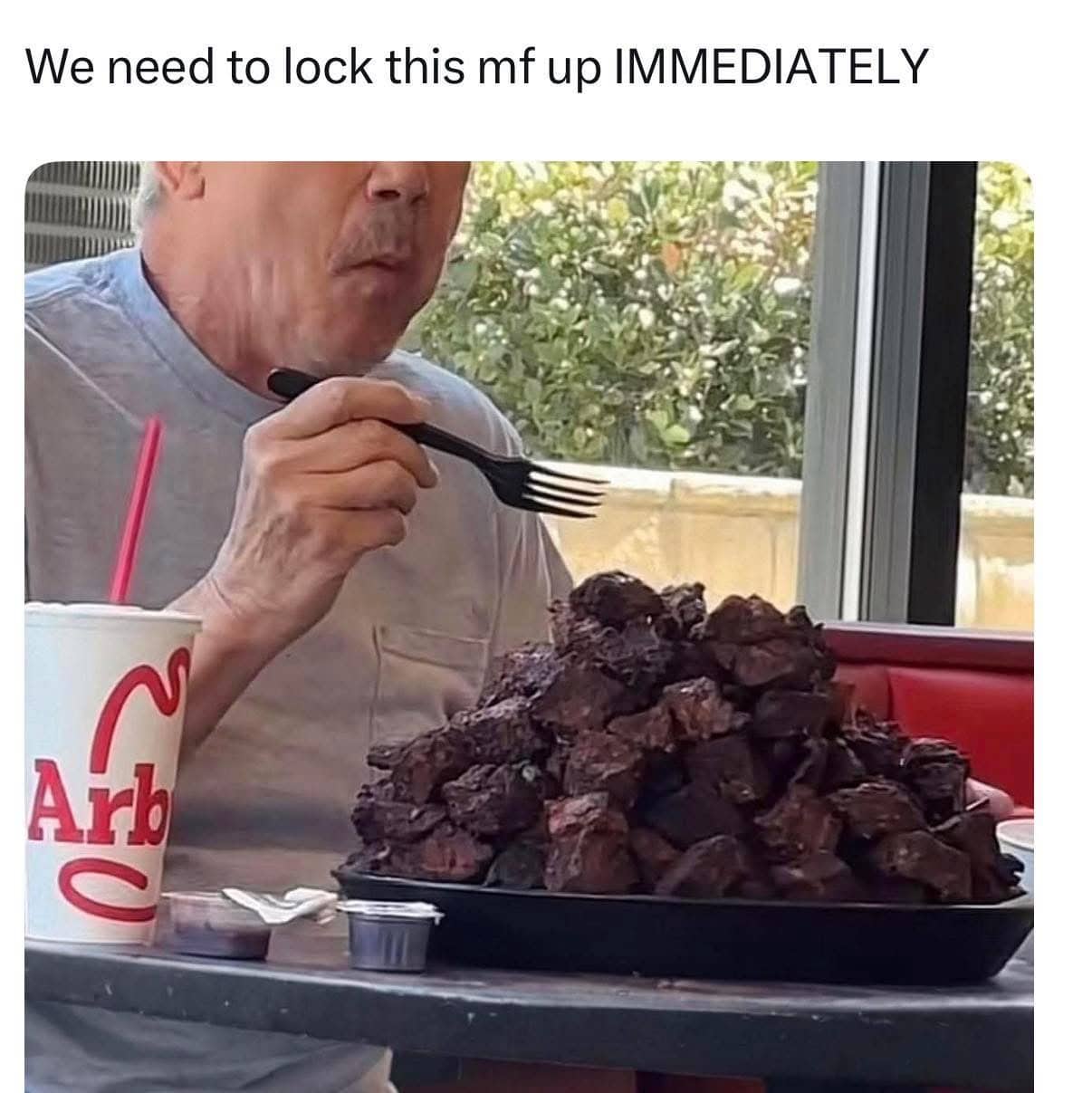 Man at an Arby's restaurant eating a massive pile of plain roast beef with a fork.