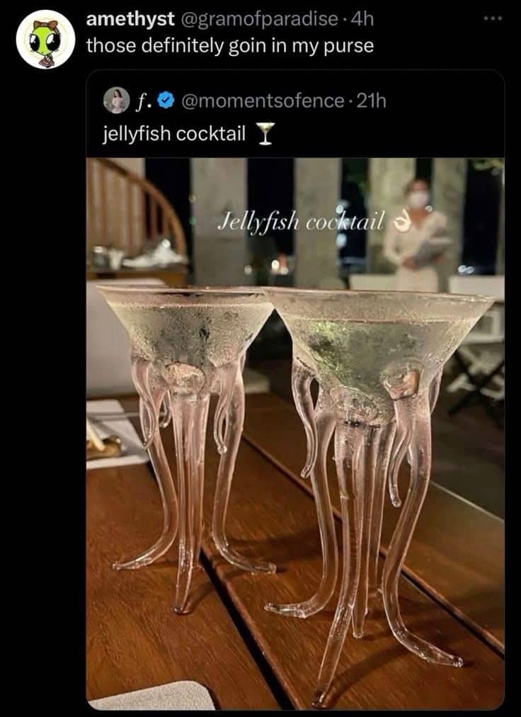 Two unique martini glasses shaped like pink glass jellyfish with tentacles resting on a wooden table.