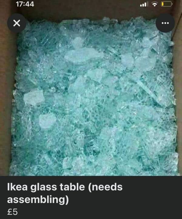 A box filled completely with shattered green tempered glass labeled as an unassembled table.