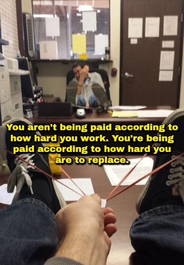 A funny shower thought post from a first-person perspective of an office worker using rubber bands stretched between their shoes to aim a paper-wad slingshot at a coworker sitting across the room, overlaid with text stating: "You aren't being paid according to how hard you work. You're being paid according to how hard you are to replace."