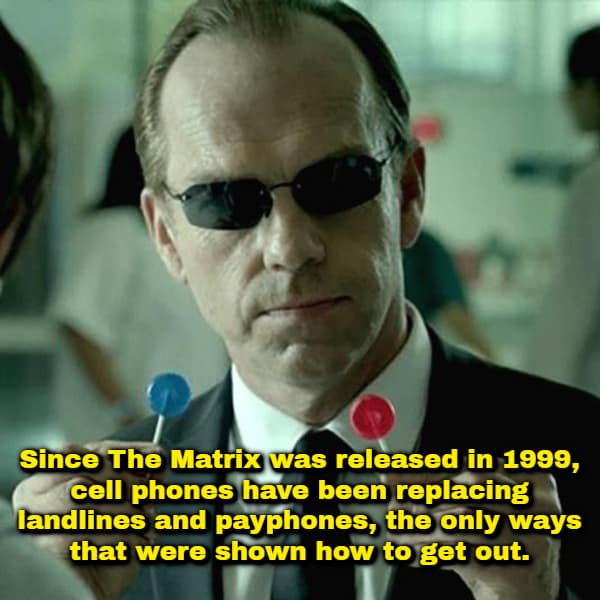 A funny shower thought cinematic layout showing Agent Smith from The Matrix wearing sunglasses and holding up a red lollipop in one hand and a blue lollipop in the other, captioned: "Since The Matrix was released in 1999, cell phones have been replacing landlines and payphones, the only ways that were shown how to get out."
