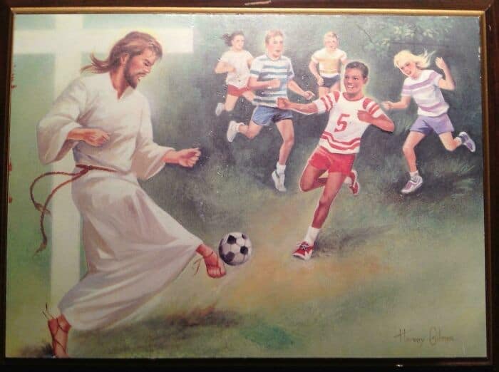 A wildly anachronistic funny thrift store find capturing a framed Christian art print where a historically dressed Jesus Christ is energetically kicking a modern black-and-white soccer ball while playing a lively match with mid-century American children in shorts and striped tees.