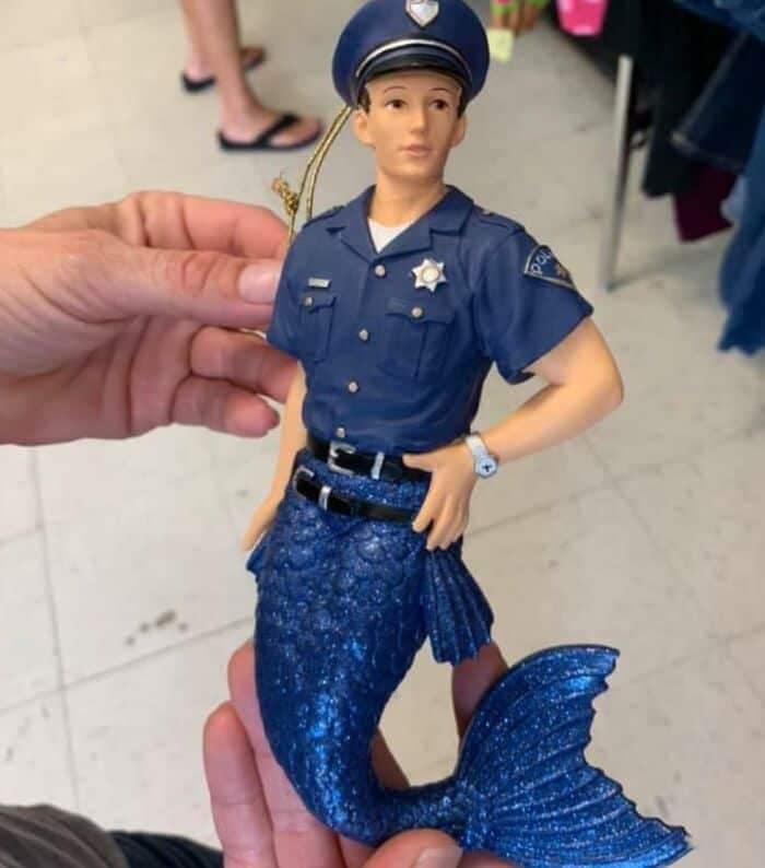 A truly baffling holiday ornament discovered as a funny thrift store find, showing a Christmas tree decoration of a male police officer in full uniform from the waist up, but possessing a sparkling blue glitter mermaid tail from the waist down.