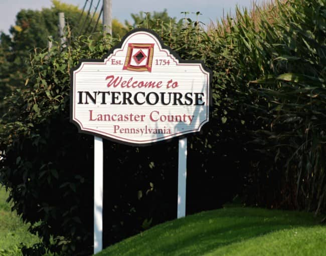 Elegant white sign welcoming visitors to Intercourse in Lancaster County, Pennsylvania.