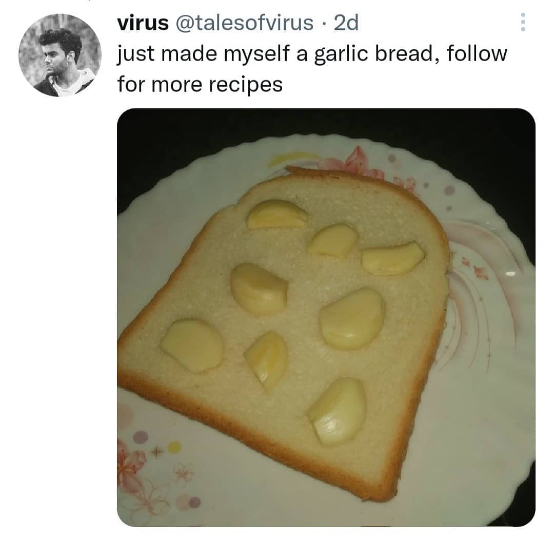 Cursed culinary recipe tweet featuring raw whole garlic cloves resting on a single piece of white sandwich bread.