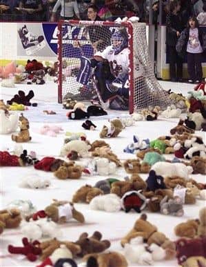 Funny hockey meme showing a goalie sitting inside a net completely surrounded by stuffed teddy bears.