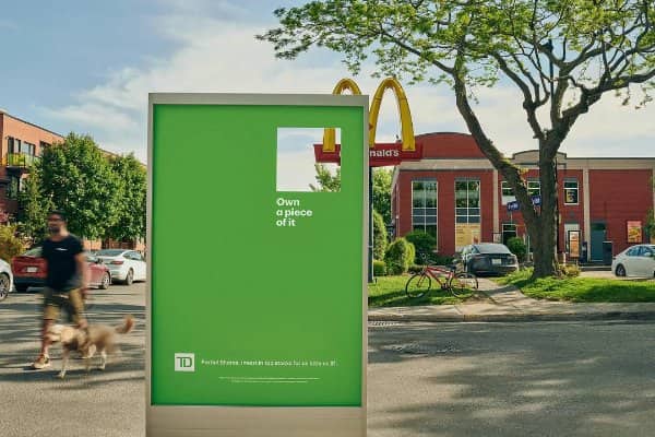 Green investment billboard with a cut out section perfectly framing a nearby fast food sign.