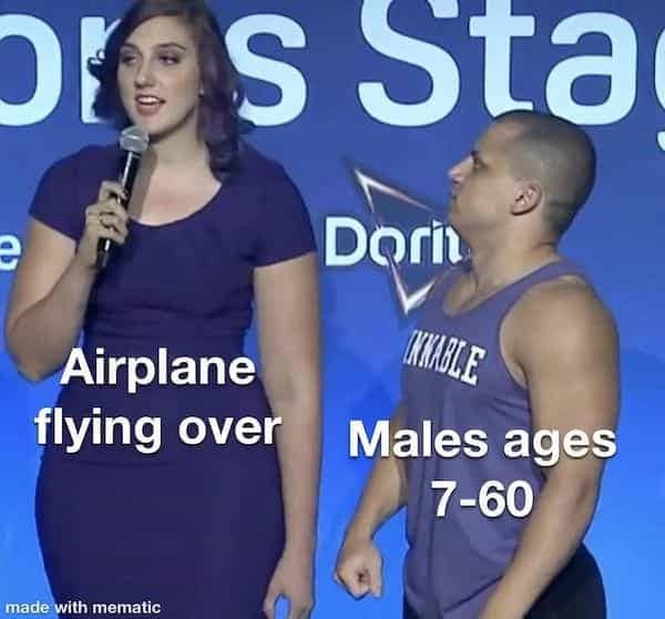 A tiny man looking up at a massive woman talking into a microphone.