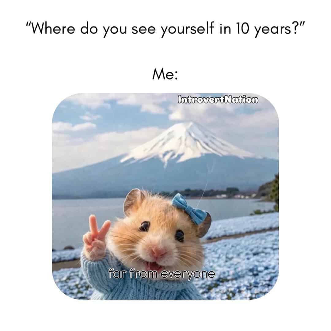 Cute hamster wearing a blue bow gesturing peace in front of a scenic snowy mountain peak.