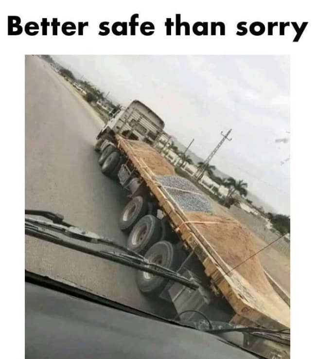 A flatbed truck transport trailer carrying a tiny pile of loose gravel held down by straps.