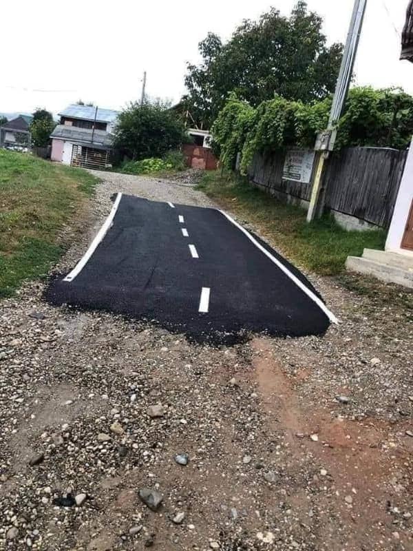 A tiny patch of perfectly paved asphalt road laid down in the middle of a gravel path.