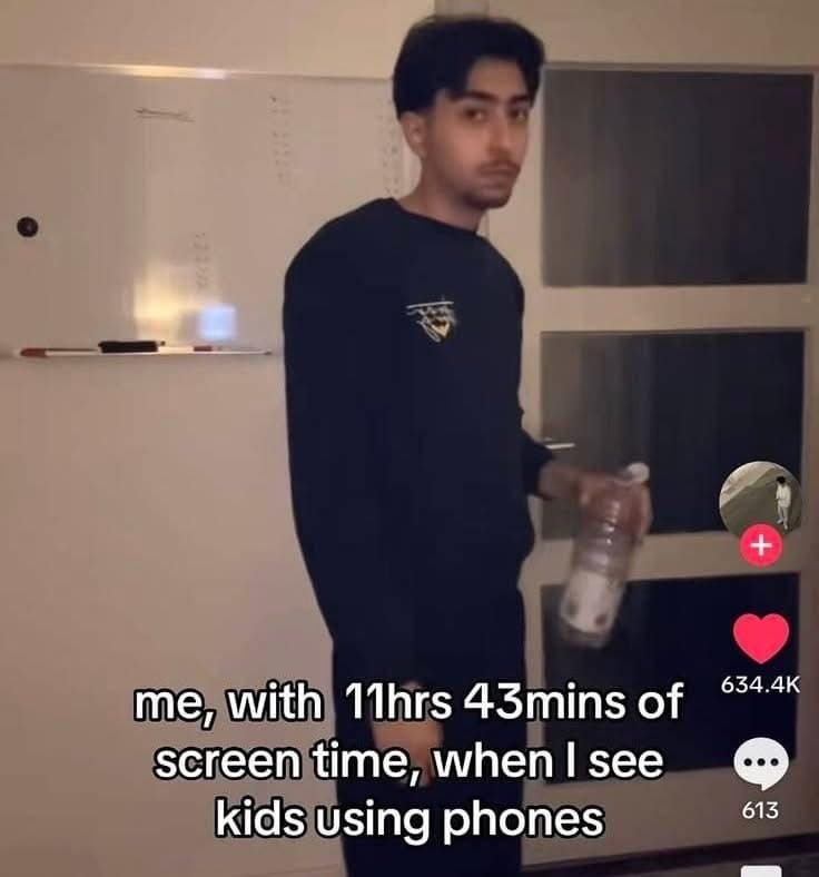 A video-sharing frame from a funny meme format showing a young man looking back with mild guilt while holding a plastic water bottle, captioned with self-deprecating text: "me, with 11hrs 43mins of screen time, when I see kids using phones".