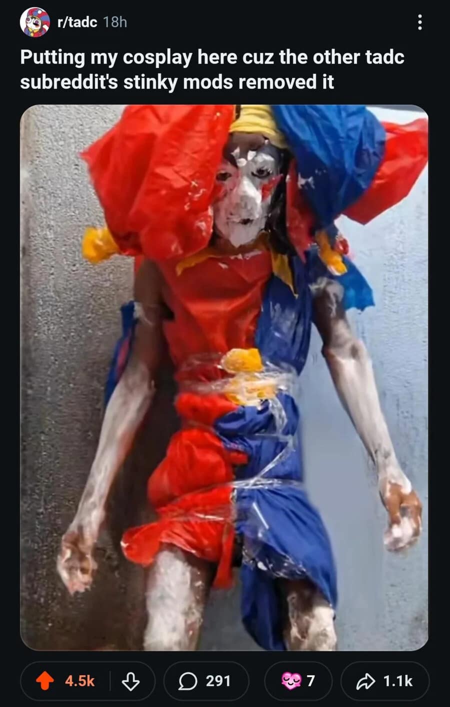 Reddit screenshot from a meme dump displaying a chaotic, low-budget DIY cosplay of Pomni from The Amazing Digital Circus constructed entirely out of red and blue plastic bags wrapped in clear packing tape.